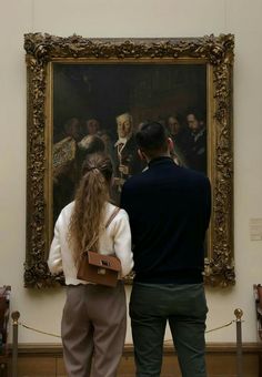 a man and woman standing in front of a painting