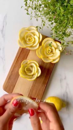 a person holding a lemon in front of flowers on a cutting board