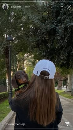 a woman is holding a dog on her shoulder and looking at the street light with palm trees in the background