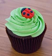 a cupcake with green frosting and a ladybug decoration on the top