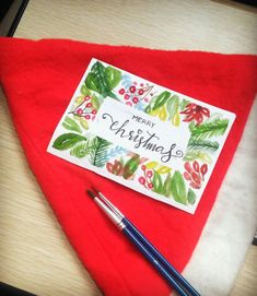 a christmas card and pen sitting on top of a red blanket