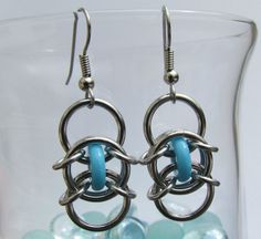 a pair of earrings with blue beads in the background