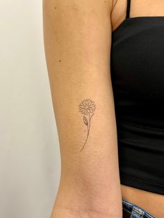 a woman's arm with a small flower tattoo on the left side of her right arm