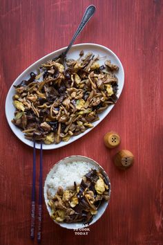 an overhead view of a plate of food with rice and chopsticks on the side