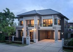 a two story house with lots of windows on the front and side of it at dusk