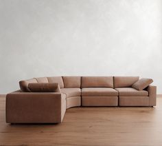 a brown couch sitting on top of a hard wood floor next to a white wall