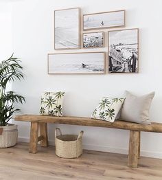 a wooden bench sitting in front of a wall with pictures on the wall above it