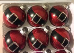 six red and black christmas ornaments in a box with silver trimmings on them