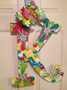 the letter k is decorated with colorful fabric flowers and ribbons on it's front door