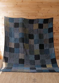 a bed with a quilt on top of it in front of a wood paneled wall