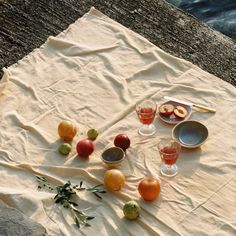 an assortment of fruits and glasses on a piece of paper with water in the background