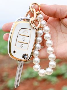 a person is holding a car key chain with pearls on it and the keys are in front of them