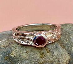 This is a vintage Sterling Silver ring with modernist design, textured  silver band and a ruby red stone.  This ring is perfect for stacking and is stamped 925 for Sterling Silver.  UK size O, US size 7.25  Graduated band width: 3-6mm   Weight 4.3g Very good vintage condition Please study the photographs where I try to show as much detail as possible. Any damage or obvious imperfections will be clearly stated. Any boxes in the photos are for display only. I offer FREE SHIPPING on all of my listings. I have lots more lovely charms and jewellery, visit my Etsy store here and take a look! https://www.etsy.com/uk/shop/LittleVintageCharmCo Any orders can be gift wrapped or gift boxed for a small charge, please ask. Vintage Sterling Silver Ruby Ring, Heirloom Handmade Sterling Silver Ruby Ring, Handmade Antique Sterling Silver Ruby Ring, Heart Eternity Ring, Silver Multi-stone Ruby Ring In Sterling Silver, Vintage Silver Ruby Ring, Hallmarked, Vintage Sterling Silver Rings, Beaded Pendant Necklace, Silver Heart Necklace