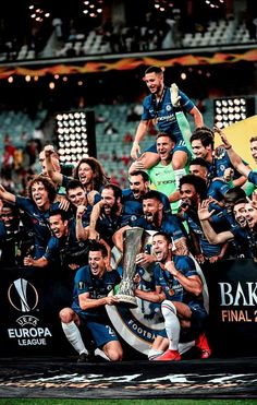 the soccer team is celebrating with their trophy and posing for a group photo in front of an audience