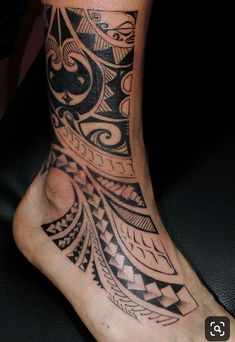 a person with a tattoo on their foot that is sitting on a black surface and has an intricate design on it