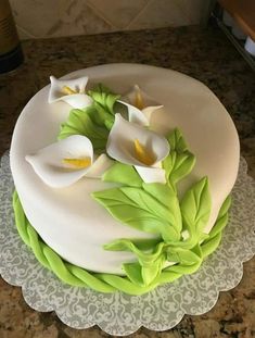 a white cake with green leaves and flowers on it