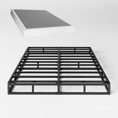 a black metal bed frame next to a white book on top of the mattress cover