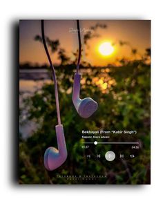 two earphones hanging from a string with the sun setting in the distance behind them