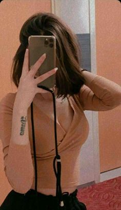 a woman taking a selfie in front of a mirror with her cell phone up to her ear