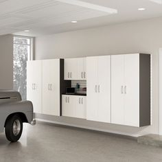 a car parked in a garage next to white cabinets and cupboards on the wall