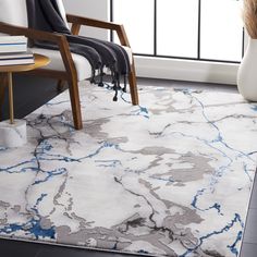 a white and blue area rug in a living room with a chair, table and window