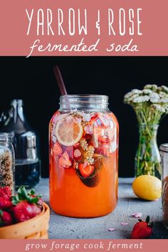 a jar filled with liquid next to flowers and fruit