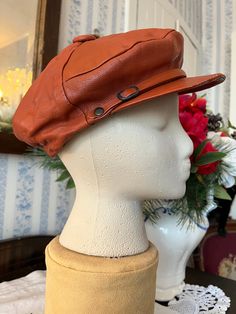 This very cool cap is made of soft leather in rusty brown. It has a small brim with a buckle detail, elastic in the back, and it's fully lined with black fabric lining. Fits men's size small to medium or women's medium to large (the mannequin's head is 19 1/2 inches around). Please note there is a bit of wear on the brim; otherwise, the hat is in good condition. Brown Leather Hat With Leather Sweatband, Brown Leather Hat With Short Brim, Vintage Leather Brimmed Hat, Classic Brown Beret With Curved Brim, Brown Brimmed Hats With Leather Sweatband, Vintage Leather Hat With Leather Sweatband, Vintage Brown Leather Brimmed Hat, Classic Brown Beret With Short Brim, Retro Brown Leather Hat