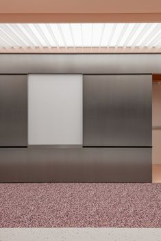 an empty room with metal partitions and pink carpeted flooring in front of it