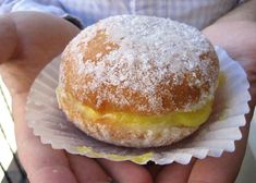 a person holding a powdered doughnut in their hands