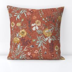 an orange pillow with floral print on it, sitting on a white table next to a wall