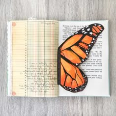 an open book with a monarch butterfly on it's cover and the pages are lined up