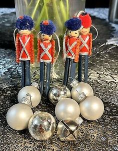 three nutcrackers with silver ornaments on a table next to a glass vase