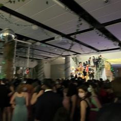 a large group of people standing around in a room with lights on the ceiling and decorations hanging from the ceiling