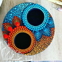 an art project with circles and dots painted on the side of a wooden table next to paintbrushes