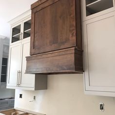 a kitchen with white cabinets and wooden cupboards above the stove top is being remodeled