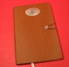 a brown book with a coin on the cover and a white cord attached to it