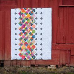 a quilt hanging on the side of a red barn