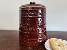 a cookie sitting on top of a wooden table next to a jar