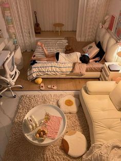 a man laying on top of a bed in a living room next to a white couch