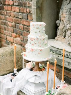 a white wedding cake sitting on top of a table next to candles and other decorations