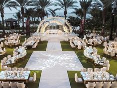 an outdoor wedding venue set up with white linens and tables, surrounded by palm trees