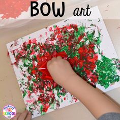 a child's hand painting with red, green and white paint on paper that says bow art