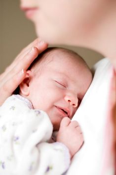 a close up of a person holding a baby in their arms and touching it's head