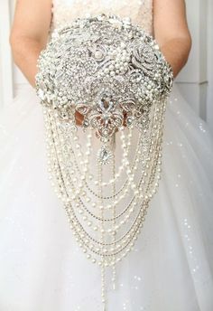 a woman in a white dress holding a bridal gown with pearls and beads on it