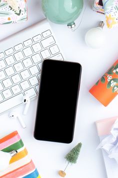 a cell phone sitting on top of a white desk next to a keyboard and mouse