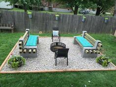 an outdoor seating area with benches and fire pit in the middle of it, surrounded by grass