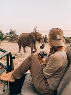 a woman sitting in the back seat of a car looking at an elephant