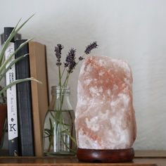 a pink rock sitting on top of a wooden table next to books and vases