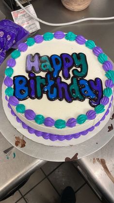 a birthday cake with purple and blue frosting on it sitting on a counter top