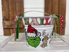 a white bucket with the grin face on it and merry christmas decorations hanging from its handle